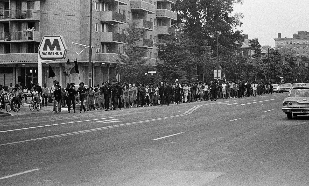 View of march as students pass gas station