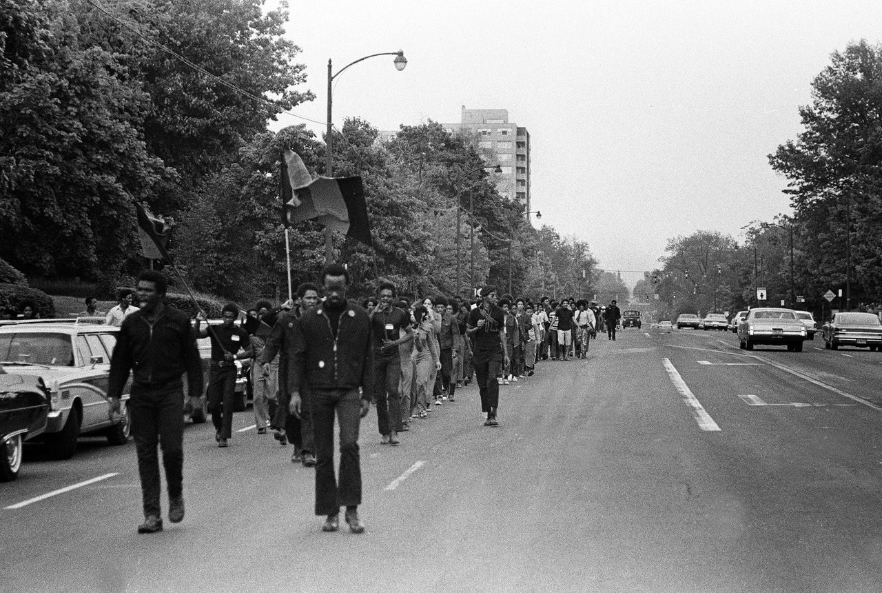 Black students march with flags down the street