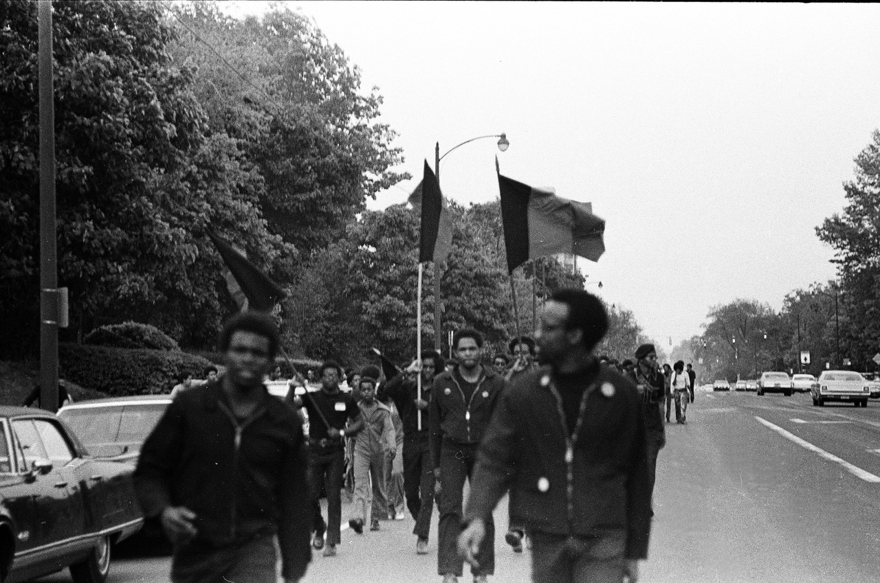 Black students march with flags down the street