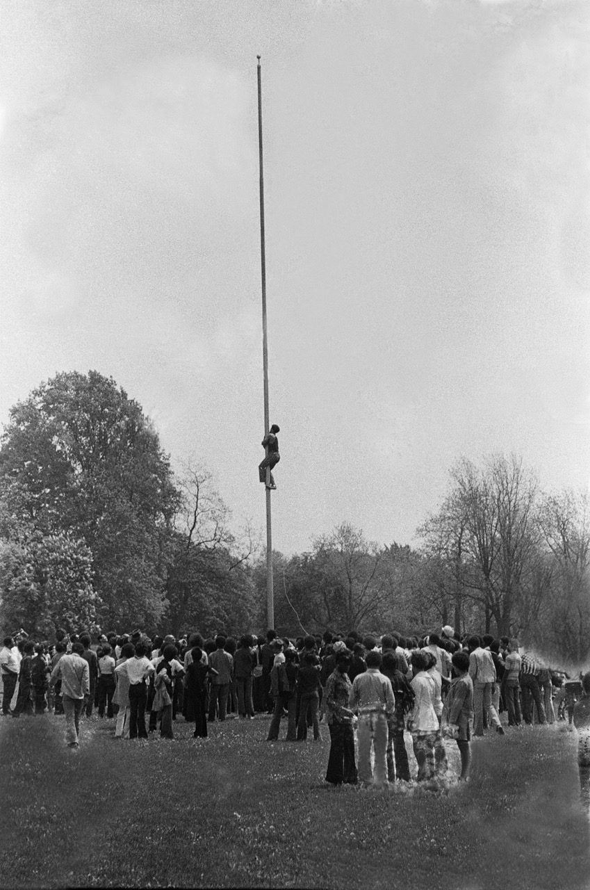 A student climbing a flagpole